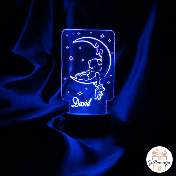 Personalizirana akrilna noćna lampa s imenom i slatkim motivom medvjedića koji spava na mjesecu. Lampa svijetli plavom bojom.