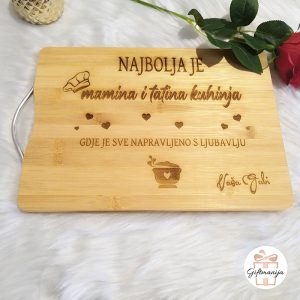 Personalizirana drvena daska za rezanje s ugraviranim natpisom "Najbolja je mamina i tatina kuhinja gdje je sve napravljeno s ljubavlju", motivima srca i personaliziranim potpisom.