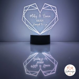 Personalizirana LED lampa u obliku geometrijskog srca koja svijetli bijelim svjetlom, s laserski ugraviranim imenima "Matej & Laura", datumom "10.11.2024." i posvetom "Zauvijek ti i ja", na crnom postolju s odrazom na površini – savršen romantični poklon za parove, Valentinovo i godišnjice.