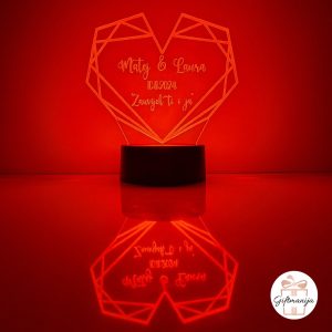 Personalizirana LED lampa u obliku geometrijskog srca koja svijetli bijelim svjetlom, s laserski ugraviranim imenima "Matej & Laura", datumom "10.11.2024." i posvetom "Zauvijek ti i ja", na crnom postolju s odrazom na površini – savršen romantični poklon za parove, Valentinovo i godišnjice.