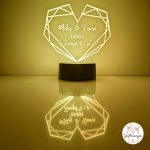 Personalizirana LED lampa u obliku geometrijskog srca koja svijetli bijelim svjetlom, s laserski ugraviranim imenima "Matej & Laura", datumom "10.11.2024." i posvetom "Zauvijek ti i ja", na crnom postolju s odrazom na površini – savršen romantični poklon za parove, Valentinovo i godišnjice.